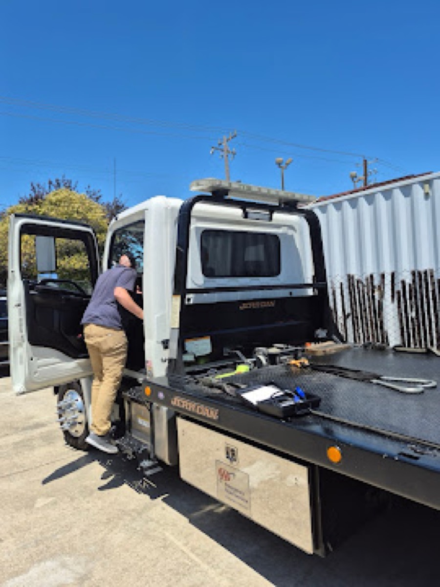 Technician performing on-site Clean Truck Check on a flatbed tow truck