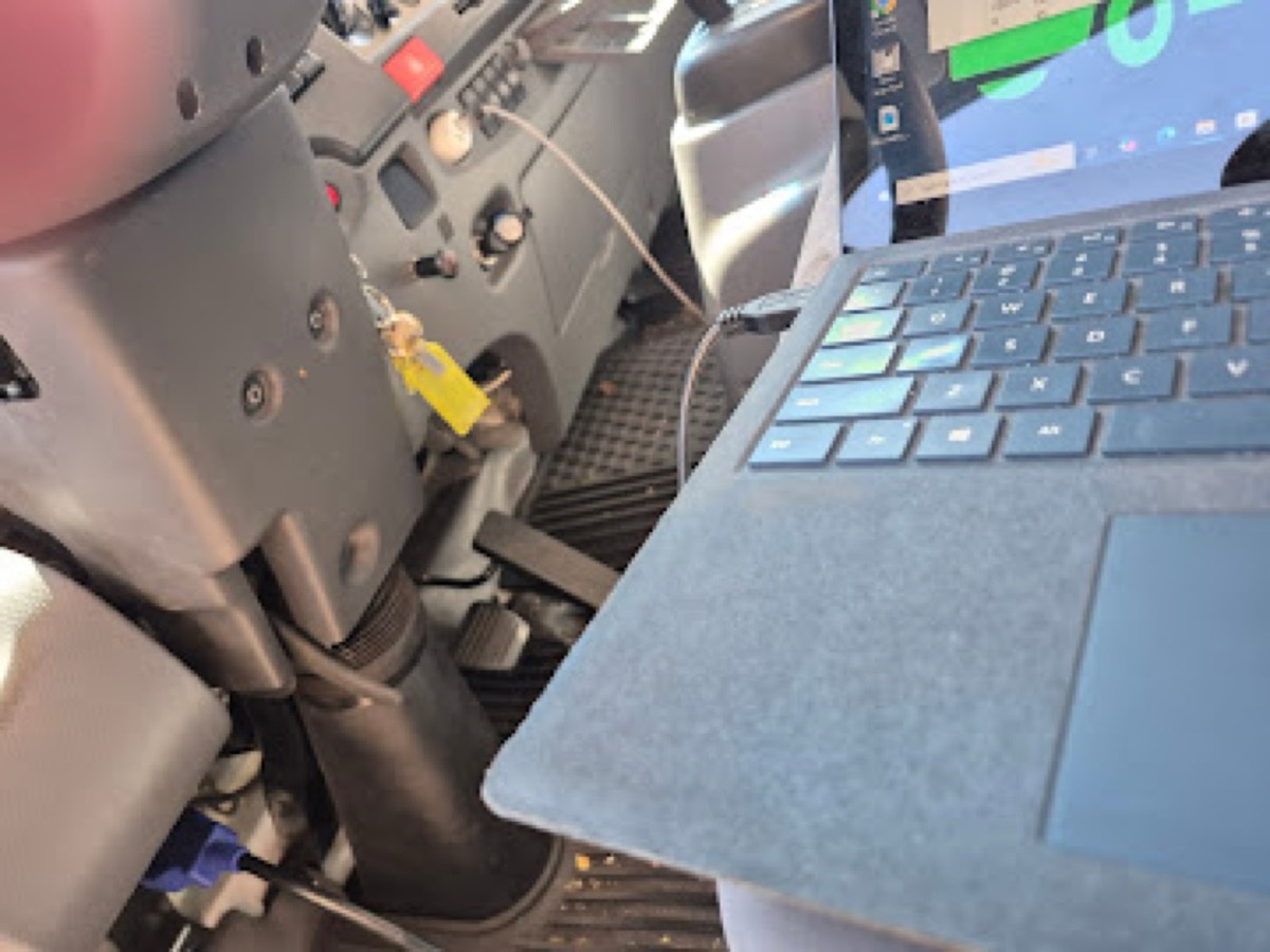 OBD diagnostic laptop connected inside a diesel truck cab during mobile testing